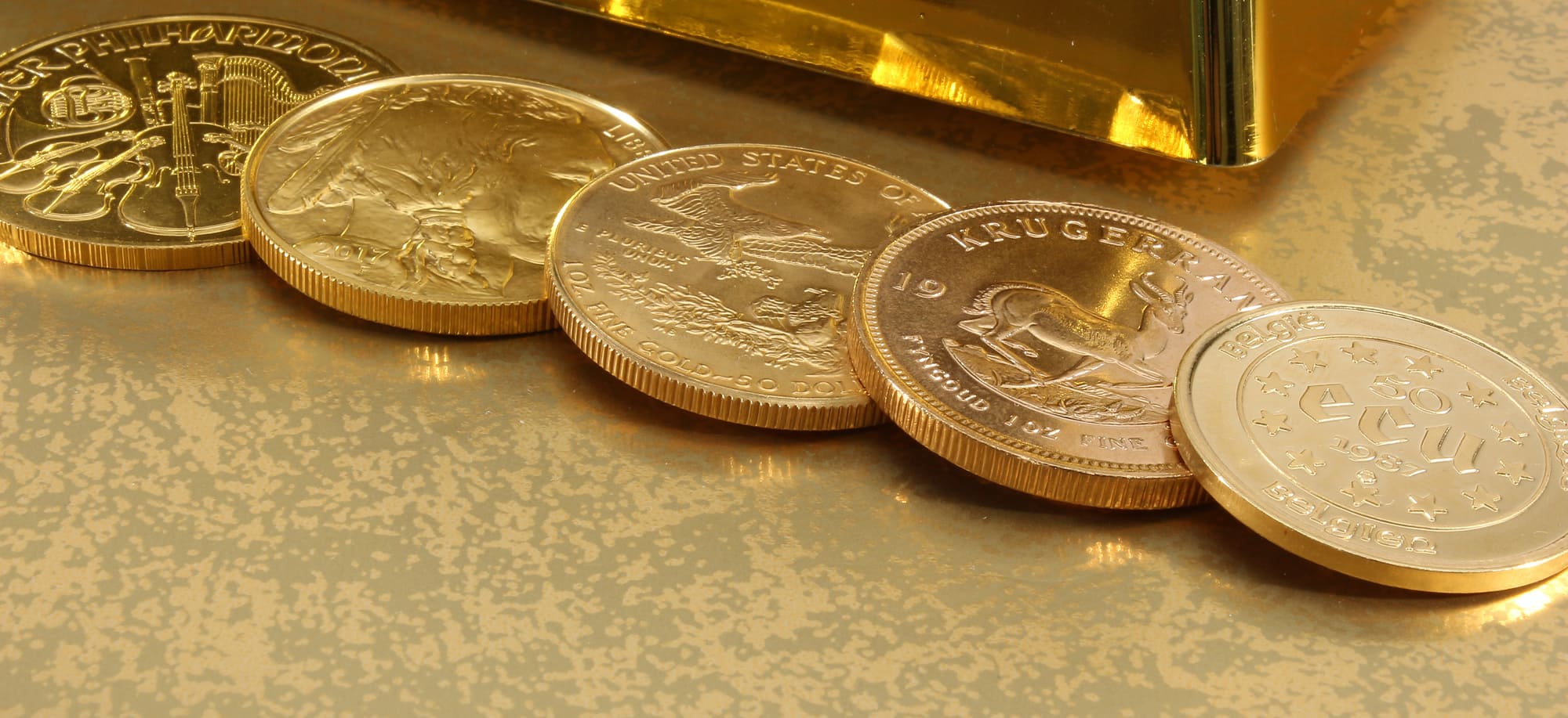 Différentes pièces d’or posées devant un lingot d’or illustrant le rachat d'or à Montréal.