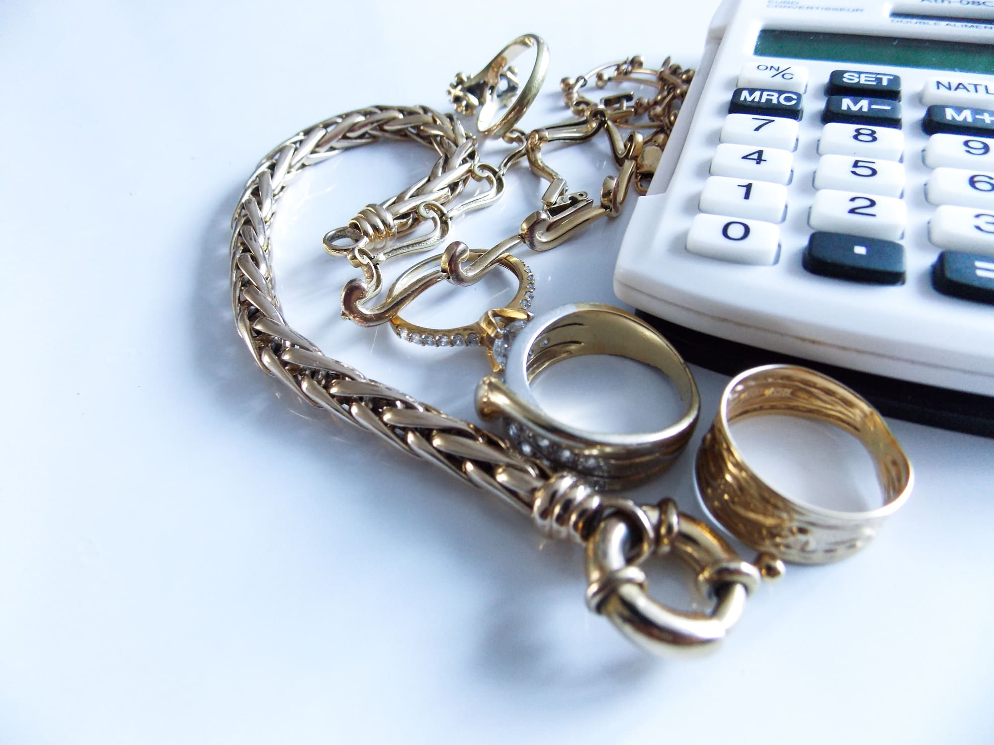 Bijoux en or à côté d’une calculatrice pour illustrer le calcul du prix de l’or lors d’un rachat.