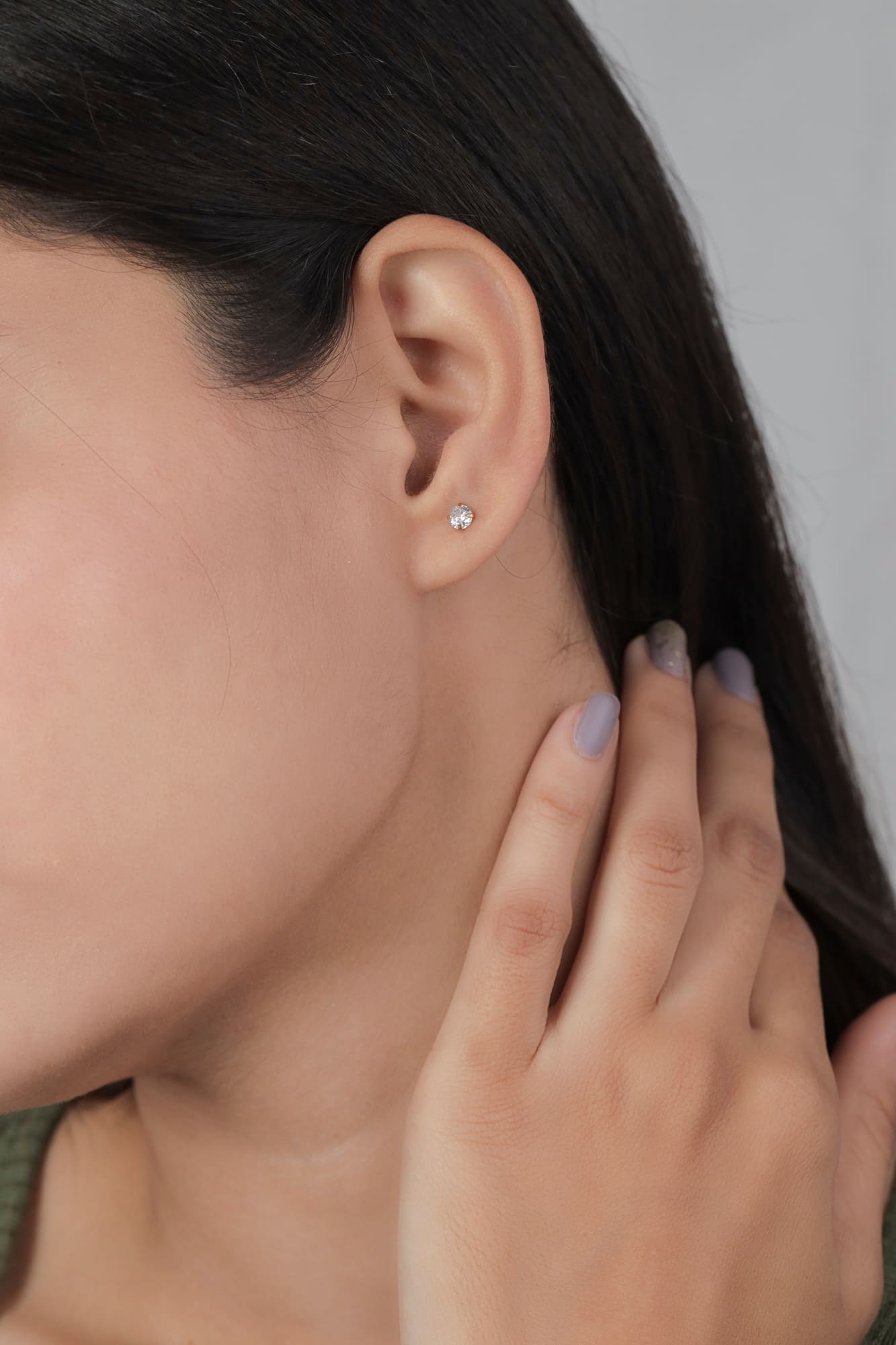 Femme portant une boucle d’oreille solitaire avec pierre brillante après un perçage d’oreille en bijouterie.